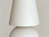 a white table lamp with a white shade on top of it
