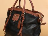 un sac à main en cuir noir et marron posé sur une table à côté d'une tasse de café