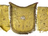 gold embroidered purse with a bird on it hanging on a wall