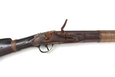 un vieux fusil exposé sur une surface blanche