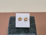 pair of gold plated flower stud earrings on a marble block