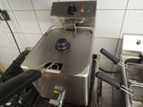 a deep fryer in the middle of a kitchen filled with frying pans