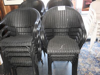 quatre chaises en osier noir posées sur un parquet
