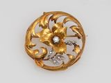 a close up of a gold brooch with a diamond in the center