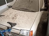 a dirty white car and a blue bicycle in a junkyard