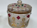 a glass container with a lid that has flowers and leaves on it