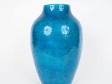 un vase bleu posé sur une surface blanche, sur fond blanc