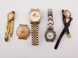 several different watches and a pen on a white surface
