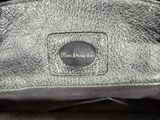 a close up of a silver purse with a black handle