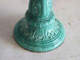 a green vase with a bird on it on a table