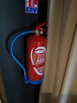 un extincteur rouge fixé à un mur noir
