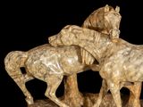 two statues of horses that are standing on a rock