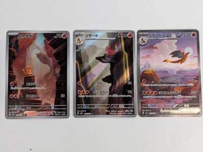 Trois cartes Pokémon sont posées sur une table blanche