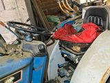 a blue tractor in a garage with a red bag on the back