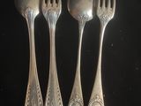 trois cuillères en argent et deux fourchettes en argent posées sur un fond noir