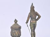 a statue of a man holding a cane next to a urn
