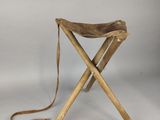 un petit tabouret en bois avec une assise en cuir, sur fond blanc