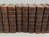 six old books stacked on top of each other on a white surface