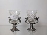 pair of silver plated wine glasses on a glass table