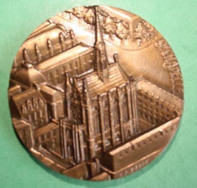 a silver medal with a picture of a city on it