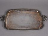 an antique silver plate with handles and handles on a gray surface
