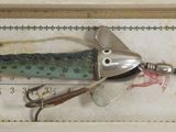 a fishing lure in a box on a ruler