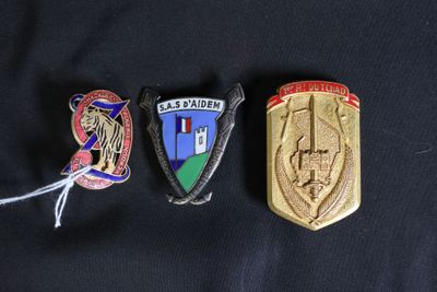 Trois badges sont représentés sur une chemise noire, l'un est un badge et l'autre est un insigne.
