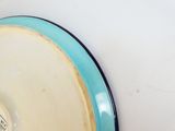 une assiette bleue et blanche accrochée à un mur blanc