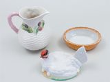 a white pitcher with a bird on it next to a bowl