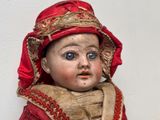 une petite poupée qui porte une robe rouge et un chapeau rouge