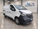 une camionnette blanche garée à l'intérieur d'un bâtiment, avec une pancarte accrochée au mur