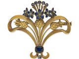 a close up of a gold brooch with blue stones