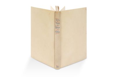 un livre ouvert, à la couverture dorée, posé sur une surface blanche