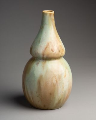 un vase vert et blanc posé sur une surface grise