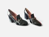 une paire de chaussures noires avec une boucle dorée au talon