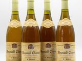 quatre bouteilles de vin sont alignées sur une surface blanche