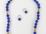 a blue beaded necklace and earring set on a white background