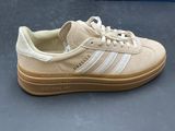 beige and white adidas sneakers on a gray surface with a blue box in the background