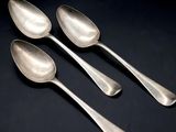 three silver spoons sitting on top of a table next to each other