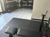 une photo d'une salle de sport avec un banc et des haltères