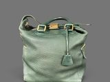 a green leather handbag with a gold buckle on the handle