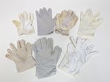 six paires de gants blancs sont alignées sur une surface blanche