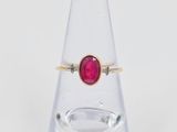 un gros plan d'une bague sertie d'une pierre rouge sur du verre transparent