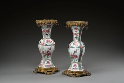 paire de vases chinois ornés de motifs floraux, posés sur des socles, sur fond gris