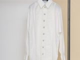 the white shirt is hanging on a clothes rack in a room