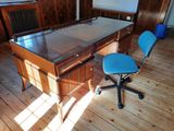 a desk with a glass top and a blue chair