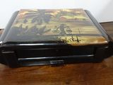 a black box with a painting on it on a wooden table
