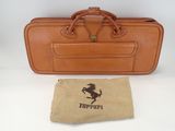 tan leather suitcase with horse logo and canvas bag on white surface