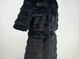 a black fur coat on a mannequin stand with a white background