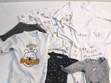 many baby clothes laid out on a white surface
